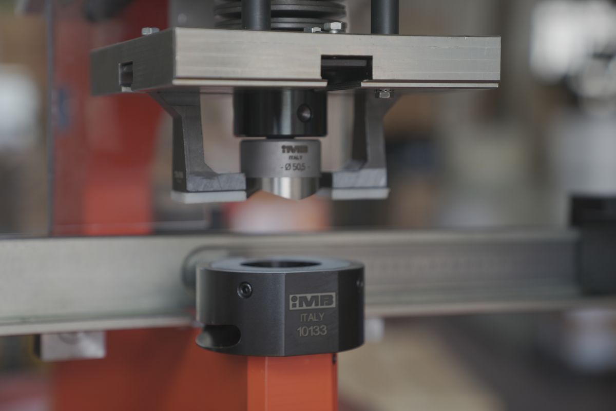 Close-up of the punch, marked IMB ITALY with a 50.5 diameter, above the black die marked IMB ITALY 10133; a steel profile runs between them.