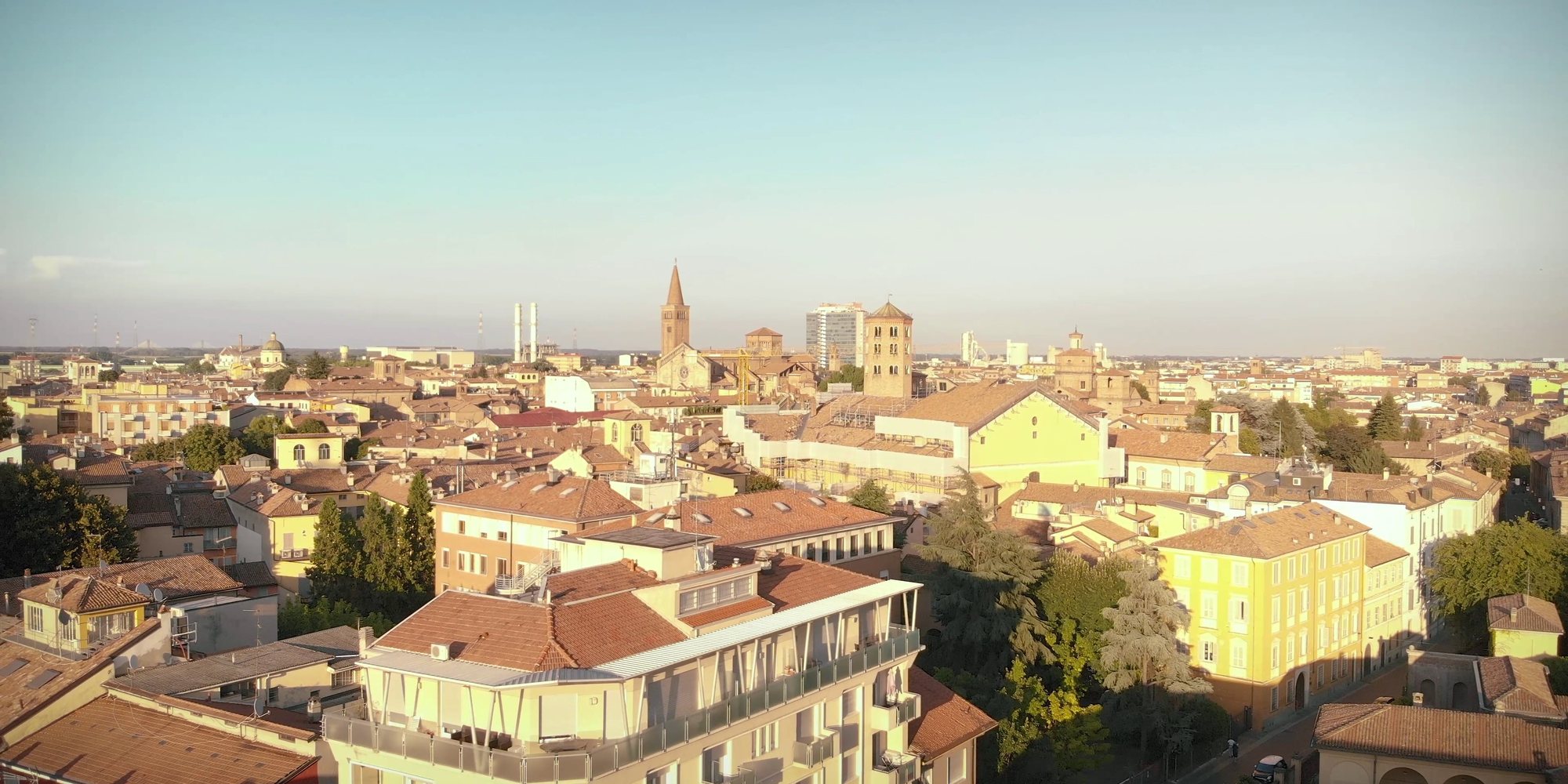 Piacenza from above in the evening light: red roofs, yellow buildings, bell towers on the horizon. A frame from the 2020 Festival trailer.
