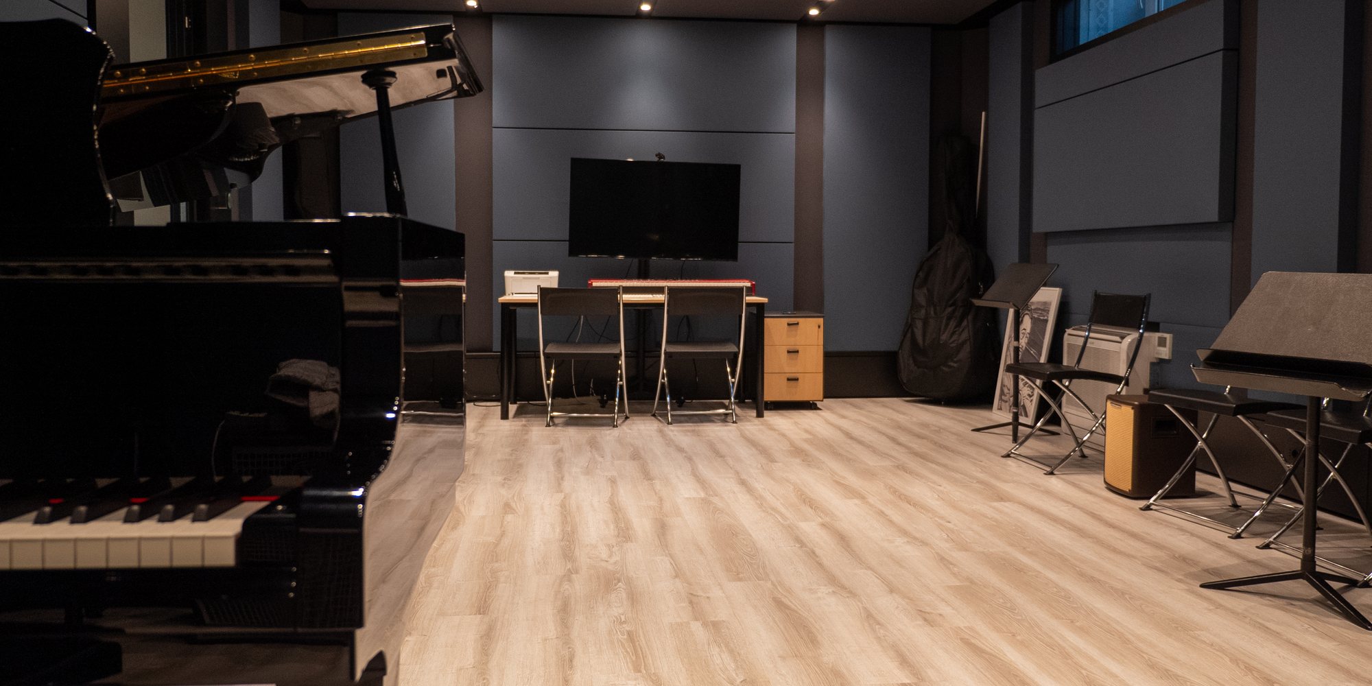 Un’aula del Conservatorio a XNL Musica, vuota: il pianoforte a coda in primo piano, il pavimento in legno chiaro, i leggii e lo schermo alla parete.