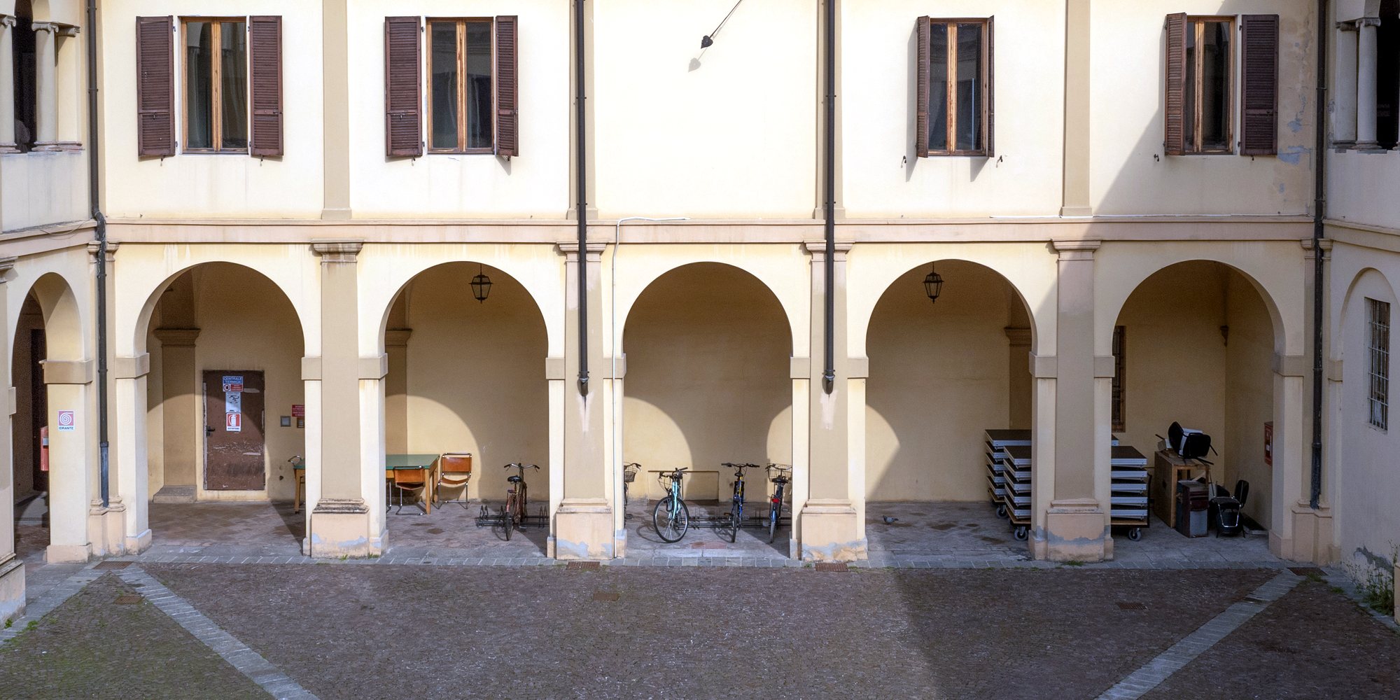 The porticoed wing of the Nicolini’s cloister by day, seen from above and in front: five arches, the pilasters, the shuttered windows on the upper floor.