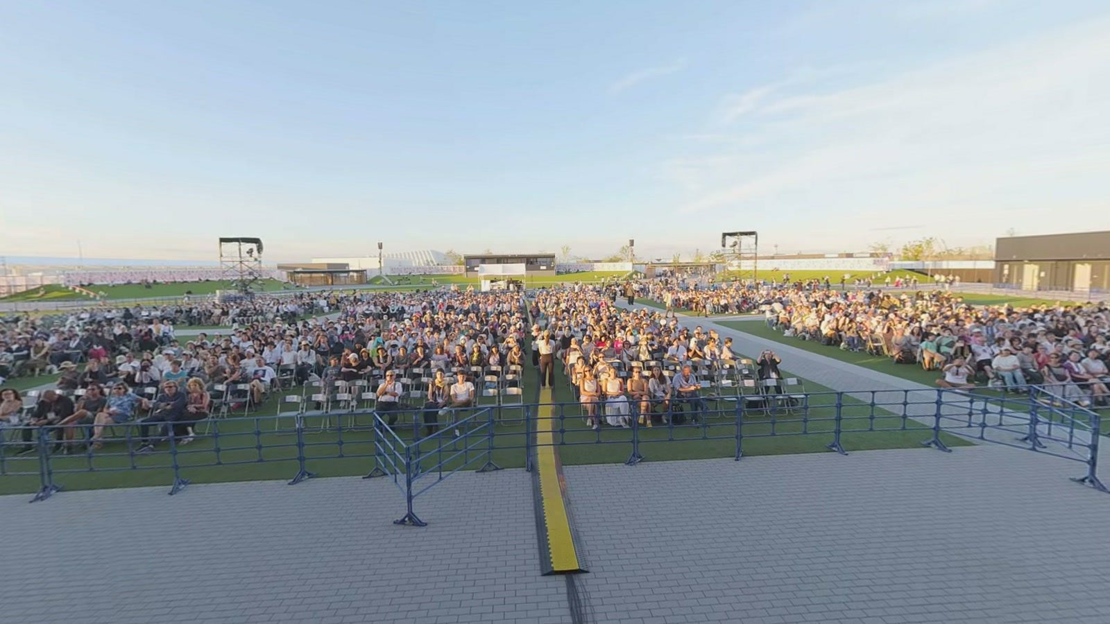 The Arena Matsuri audience seen from the stage: thousands of people seated on the lawn, at sunset.