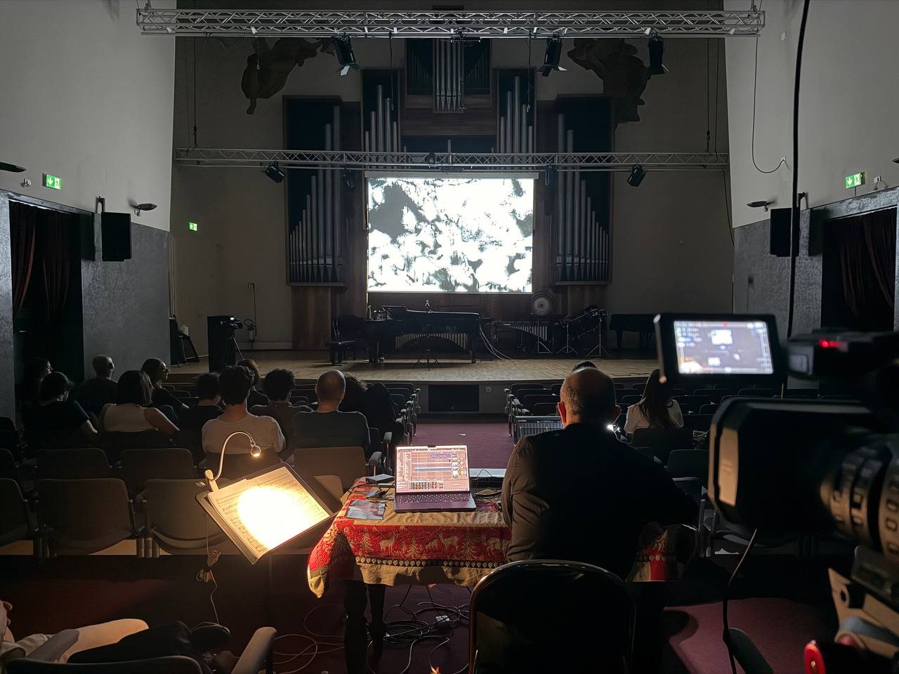 The Nicolini’s Salone during the concert “Frontiere” on 12 June 2026, seen from behind the control desk: the camera, the laptop, the lit mixer and the screen on stage.